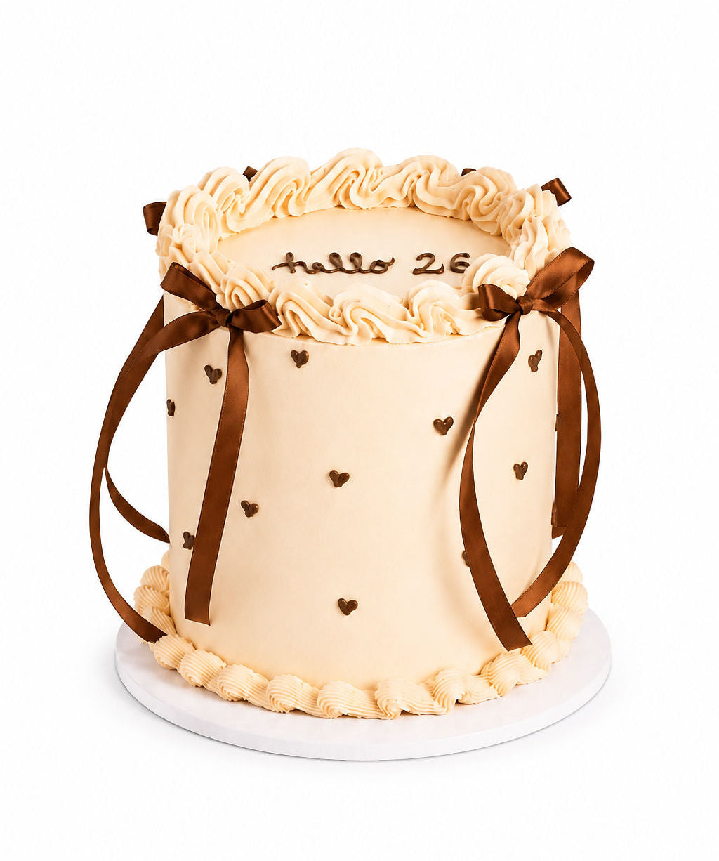 Blush pink celebration cake with a satin ribbon and piped hearts