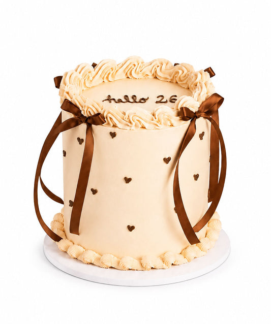 Blush pink celebration cake with a satin ribbon and piped hearts
