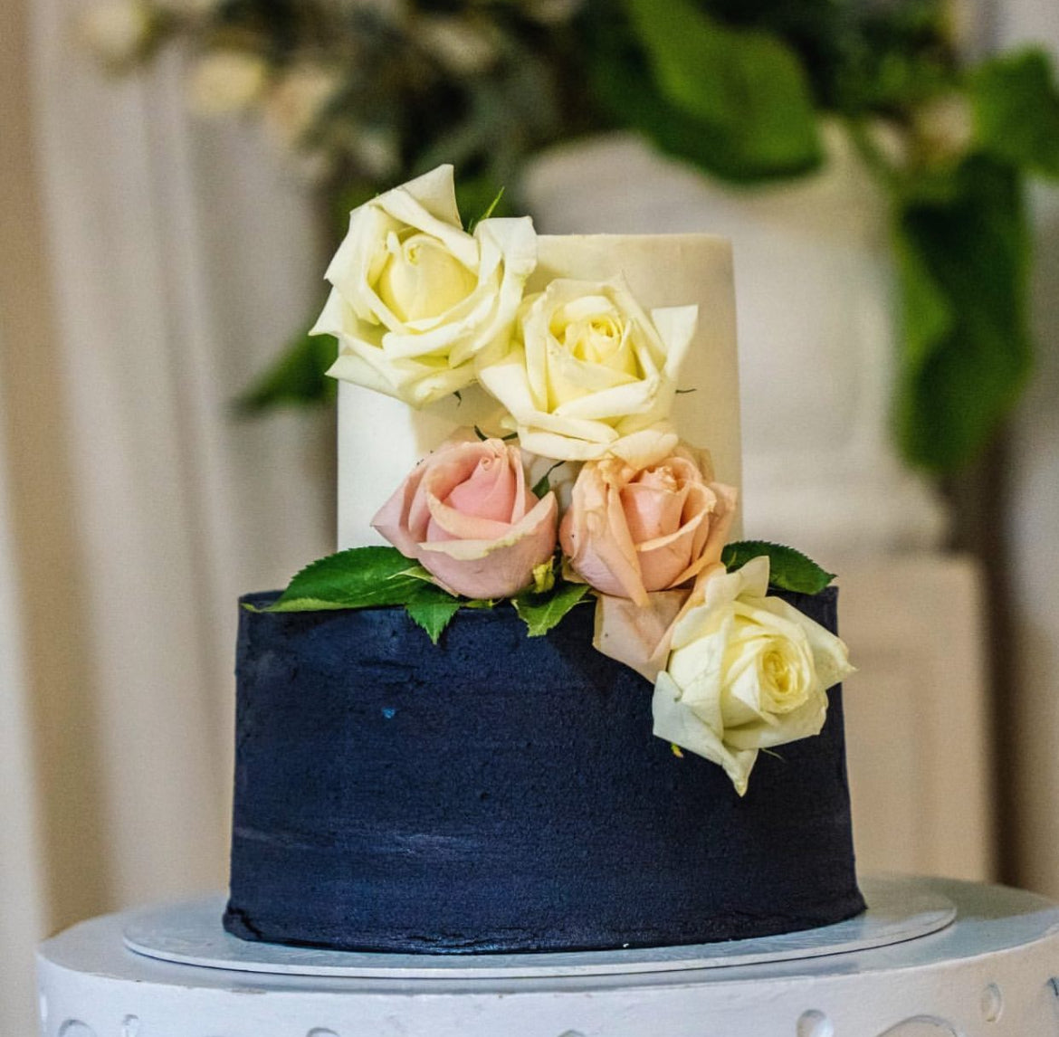 Two tier navy blue and white wedding cake dressed with fresh flowers